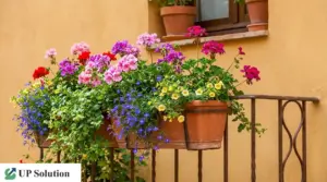 Fioriere su balcone con gerani rosa e rossi e fiori colorati in vasi di terracotta, per una fioritura continua