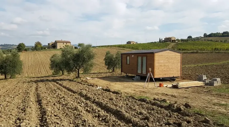 Prefabbricato in legno su terreno agricolo con campi coltivati e rilievi per possibile costruzione